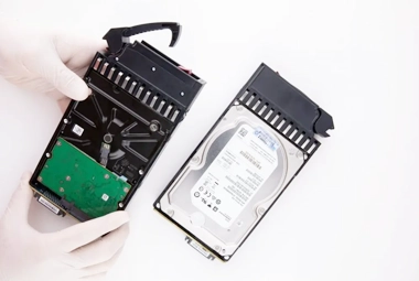 Technician inspecting a damaged RAID hard drive, examining physical and logical issues for data recovery.