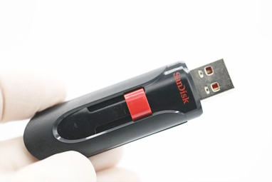 Technician working on data recovery for a SanDisk USB flash drive, using recovery software and diagnostic tools to restore lost files.