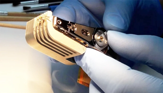 Technician in a cleanroom lab performing data recovery on hard drives with specialized equipment.