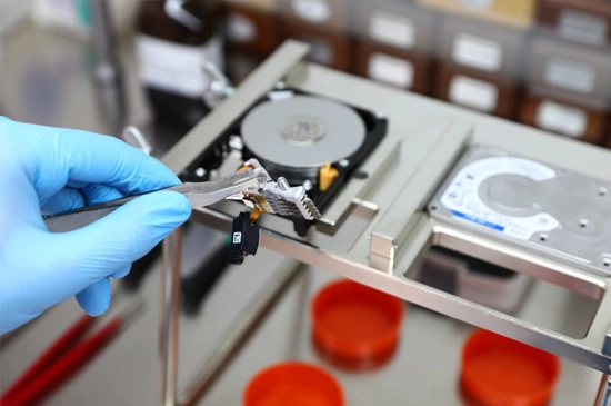 Technician in a cleanroom using specialized equipment for data recovery from hard drives.