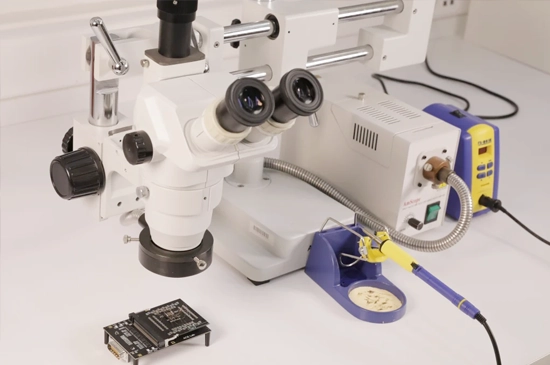 Technician using a microscope in a cleanroom with top-tier tools for data recovery, inspecting and repairing damaged drive components with high precision.