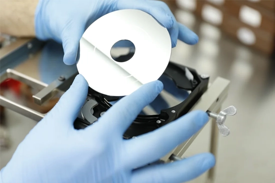 Technician performing RAID data rescue in a cleanroom environment, handling damaged RAID drives with specialized equipment to recover data.