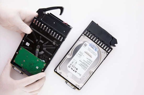 Technician working on RAID data recovery with multiple hard drives and specialized tools in a cleanroom.